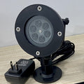 Christmas pattern projector light on its round base with the plug-in power adapter